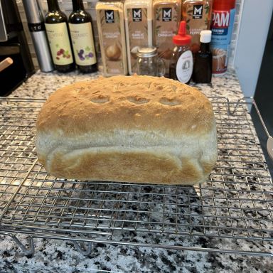 A homemade loaf of bread cooling on a wire rack